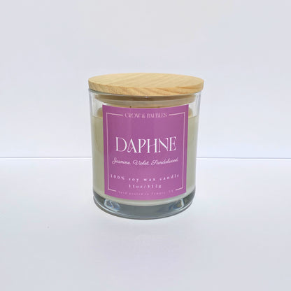Glass candle with a pink label "Daphne" on a white background
