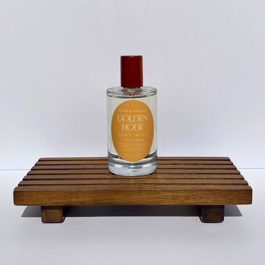 Perfume bottle labeled 'Golden Hour' on a wooden stand with a white background
