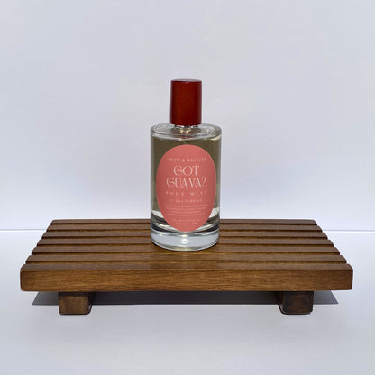 Bottle of 'Got Guava?' body mist on a wooden stand with a white background