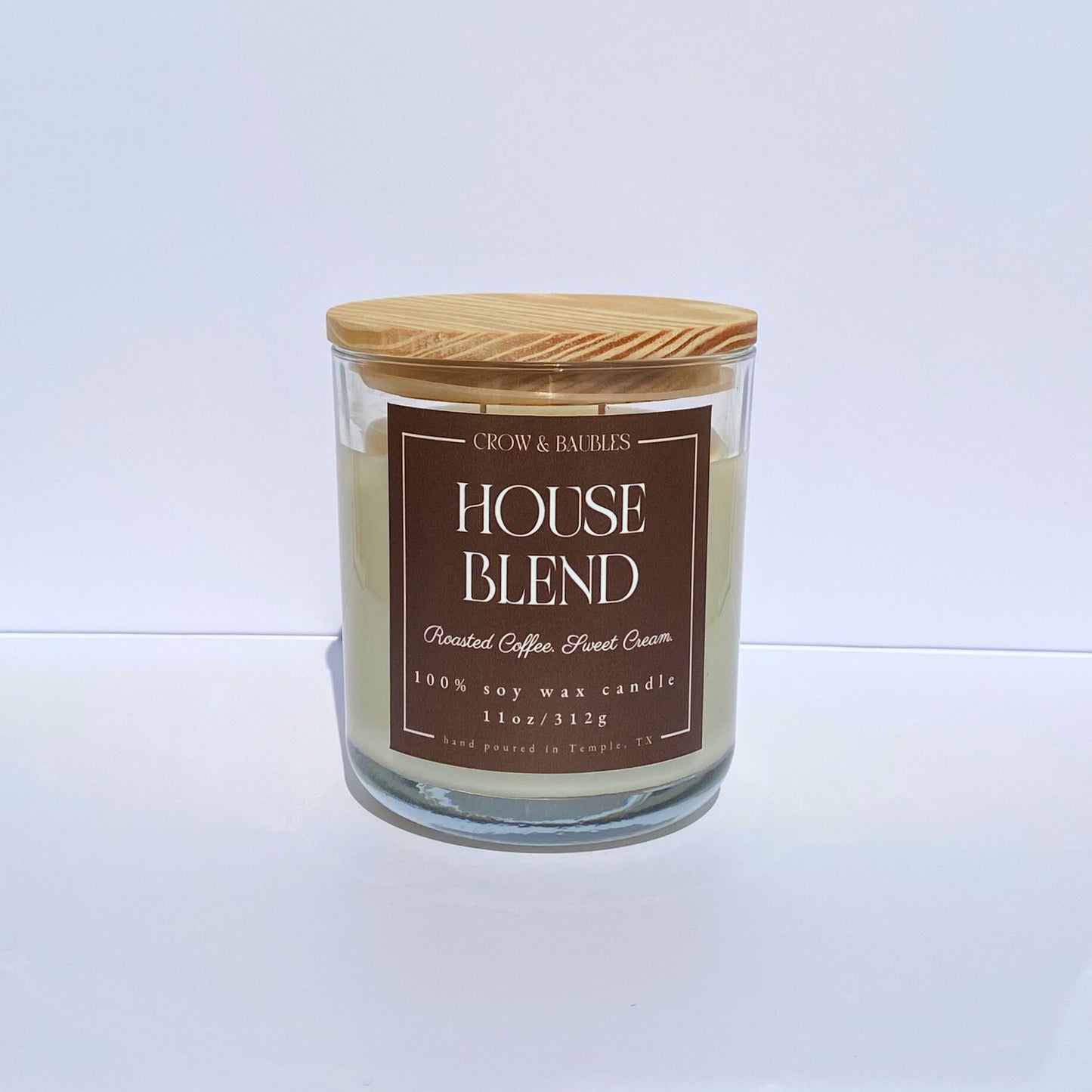 Candle with a wooden lid and brown label "House blend" on a white background