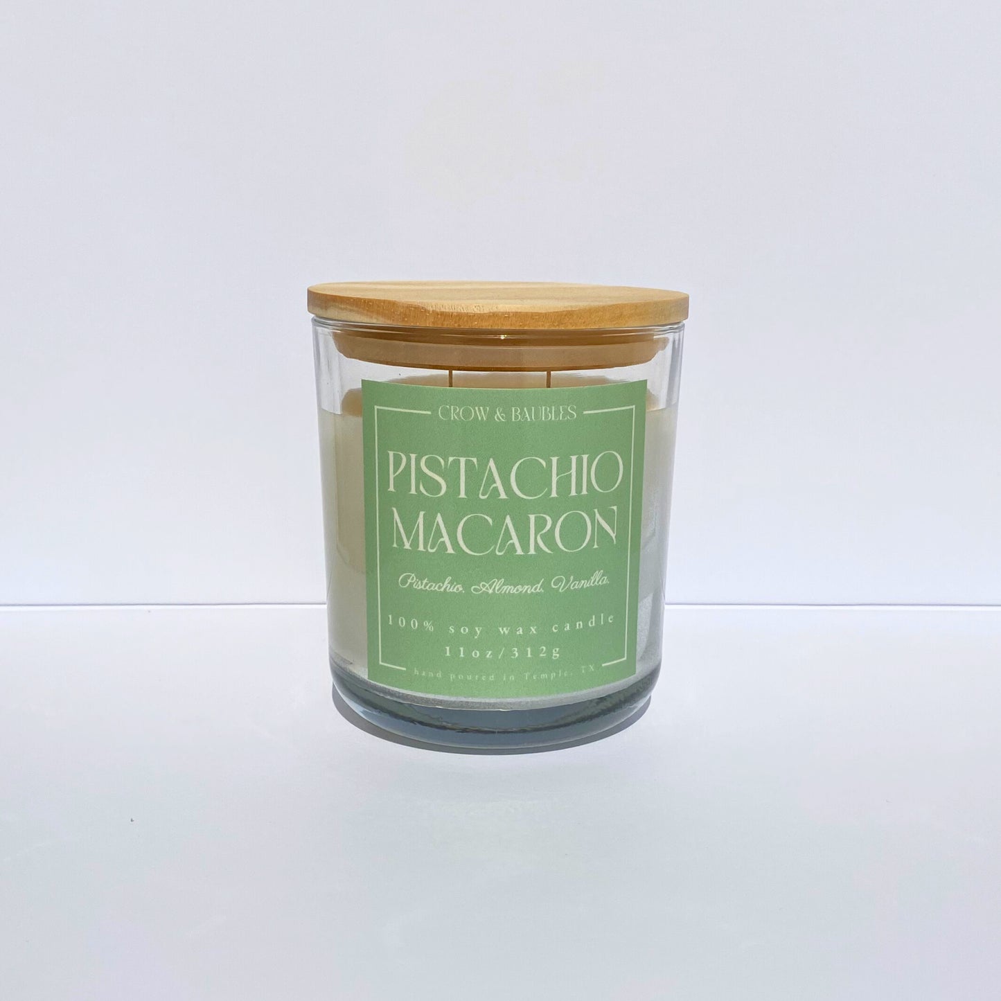 Candle with a green label "Pistachio Macaron" on a white background